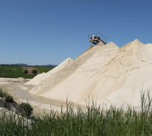 Förderband an der Spitze eines Sandhaufens schüttet Sand im Quarzsandwerk auf.