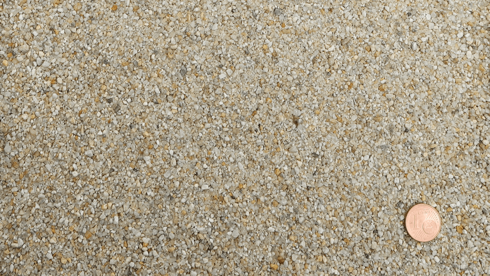 Detailansicht der Korngröße des gewaschenen Quarzsands RK I 0,25/2 GA1 von Quarzwerke Friedl – mit Münze als Größenvergleich