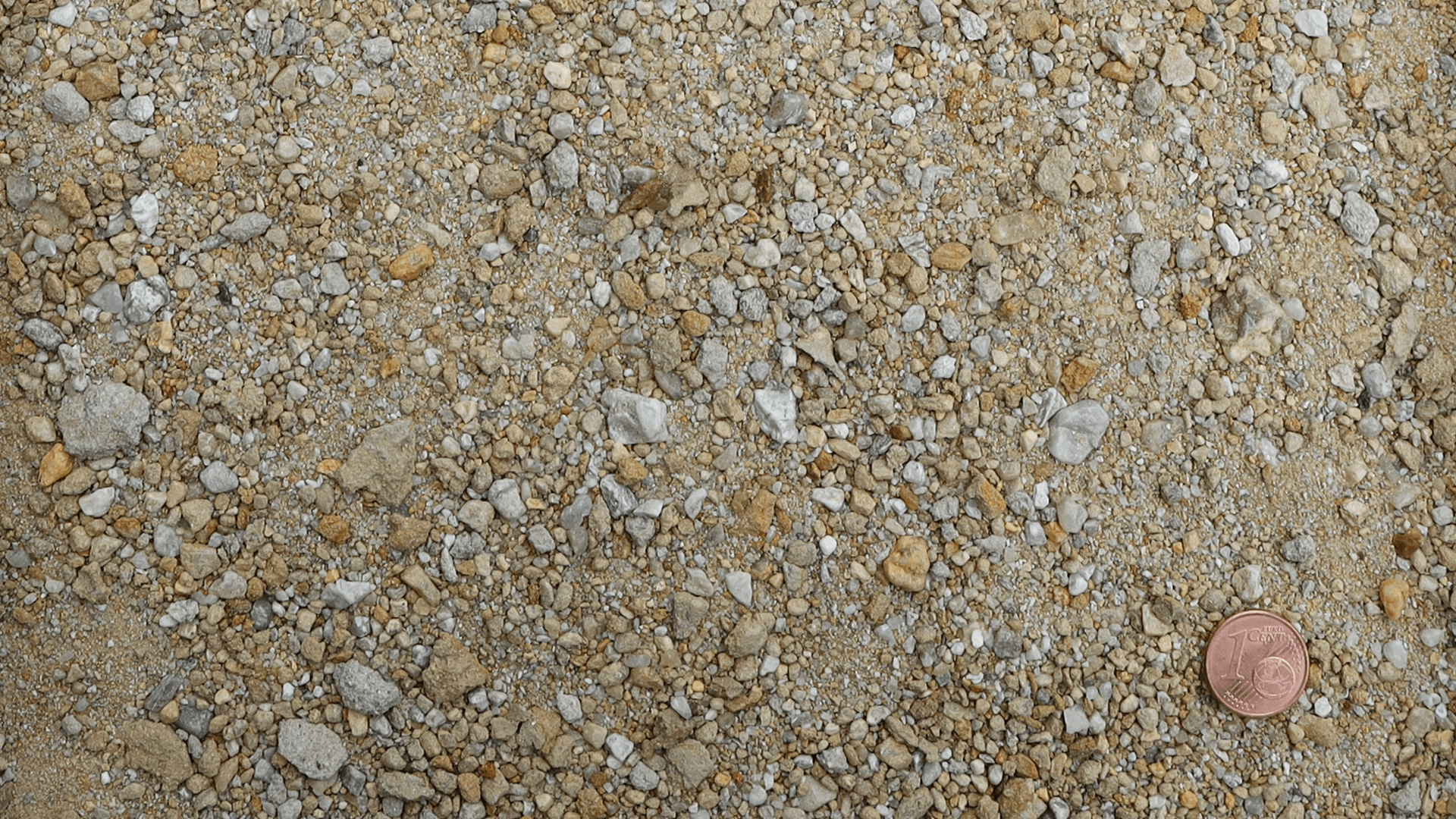 Ungesiebter Rohsand von Quarzwerke Friedl als Wandmaterial – Körnungsstruktur im Vergleich mit Centmünze